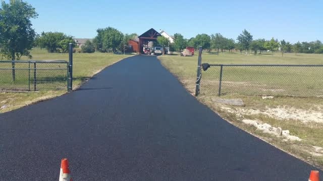 Fresh asphalt drive through a ranch gate entrance