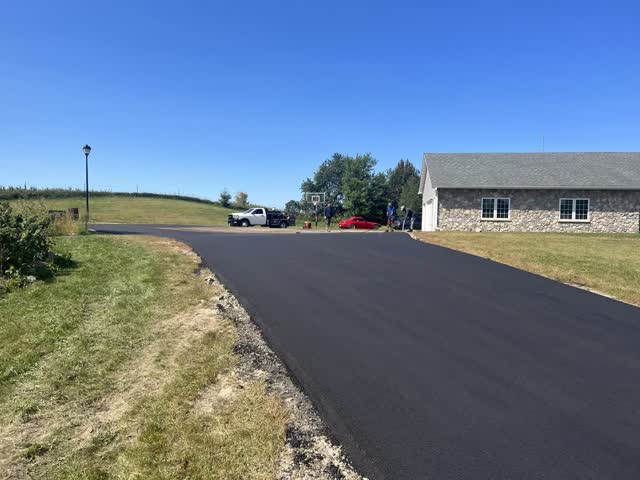 New asphalt parking pad beside a stone building